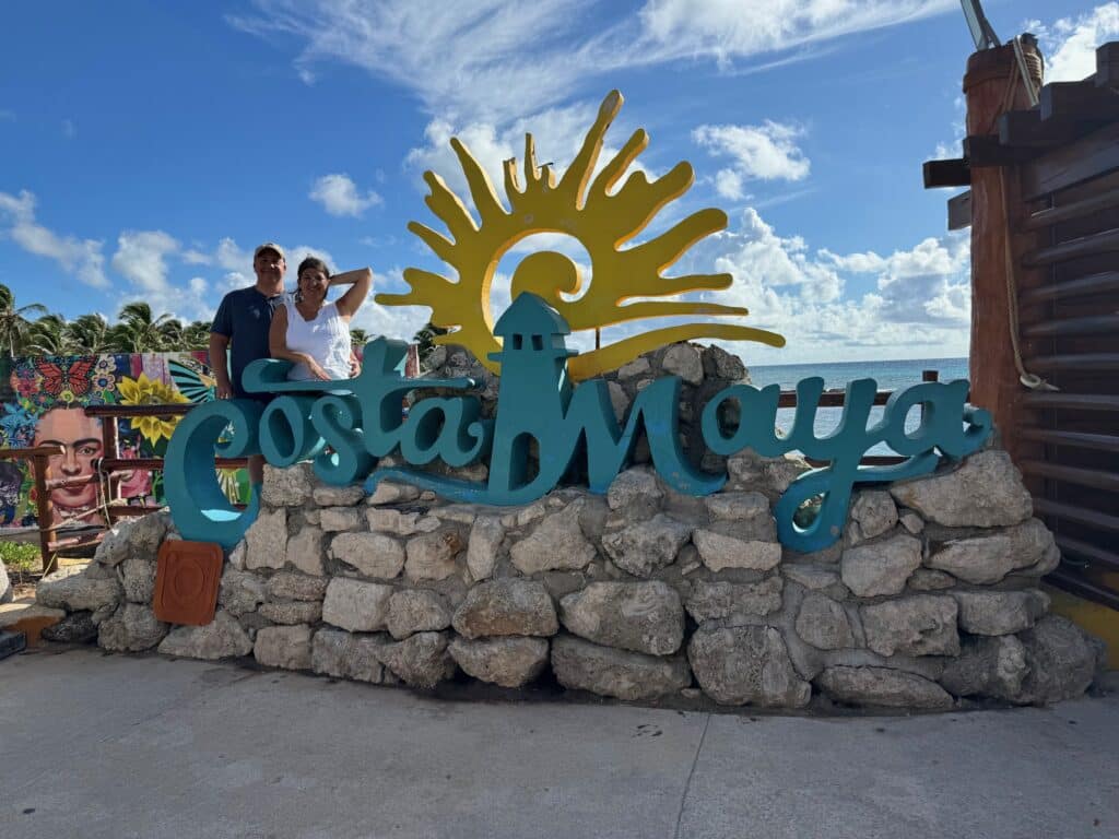 Couple standing in front of the colorful Costa Maya sign at the cruise port, reflecting the fun, welcoming atmosphere of this popular Western Caribbean stop.