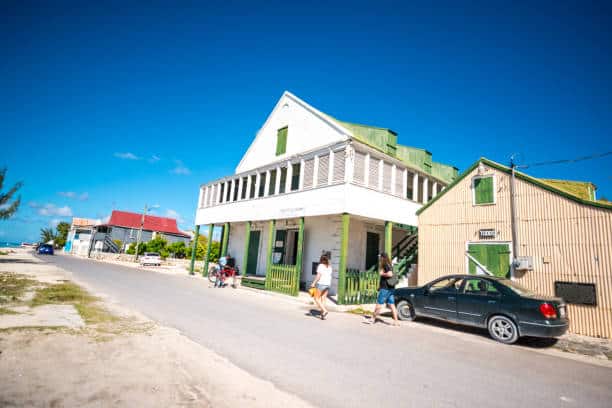 Tourists walking along the historic waterfront streets of Cockburn Town on Grand Turk, surrounded by colorful colonial buildings and ocean views