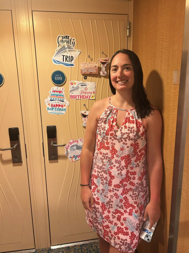 Guest standing beside her decorated cruise cabin door on her birthday, capturing a joyful birthday cruise celebration moment.