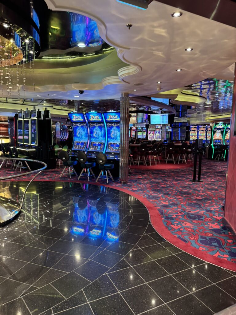 Casino Royale on Oasis of the Seas with rows of colorful slot machines, patterned carpet, and bright lighting creating a lively gaming atmosphere.