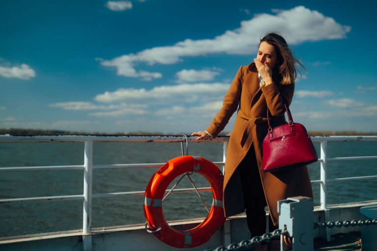 Woman on a cruise ship holding her hand over her mouth, illustrating the need for a cruise seasickness remedy.