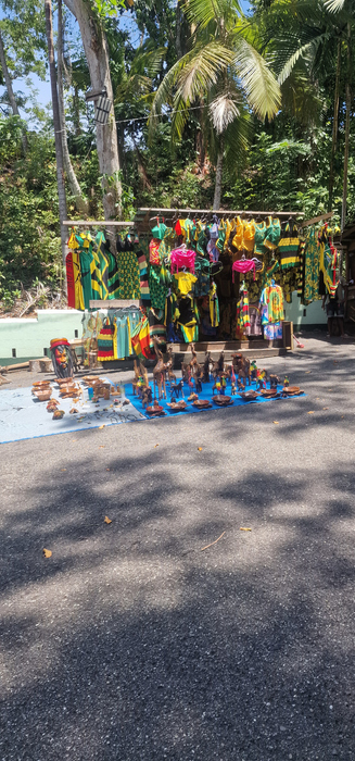 Stalls at the Dunn’s River Falls Craft Market displaying handmade Jamaican souvenirs, wood carvings, and colorful artwork.