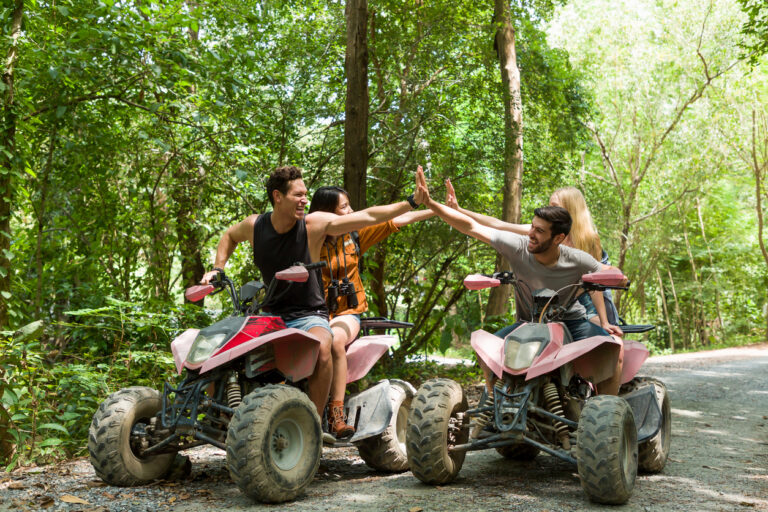 Group of friends riding ATVs along a forest trail, smiling and enjoying an off‑road adventure in the mountains