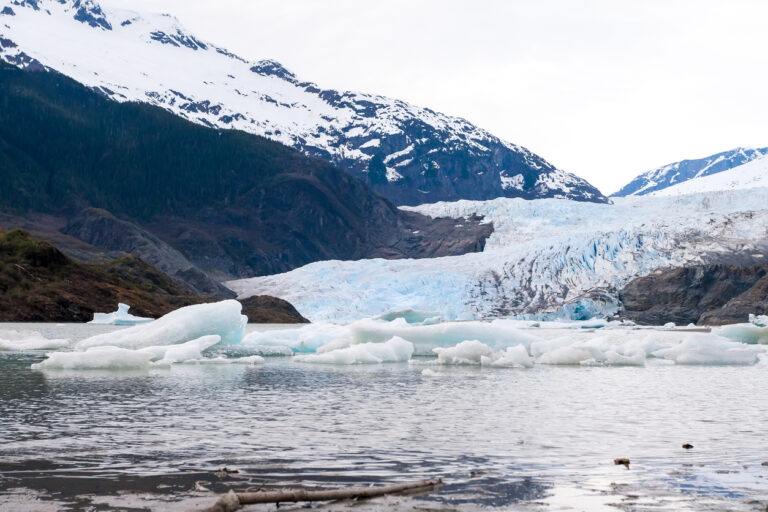 Glacier ice and floating icebergs with snow‑covered mountains near Mendenhall Glacier in Juneau, Alaska.