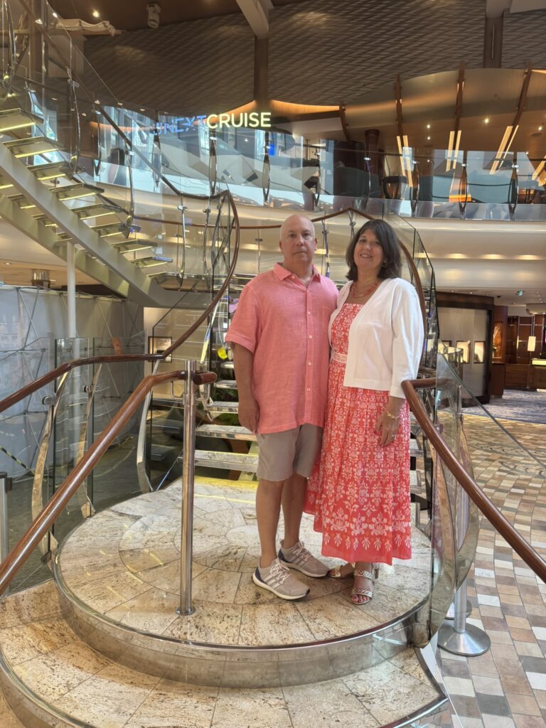 Couple standing on the staircase along the Promenade deck on Oasis of the Seas, posing for a photo.