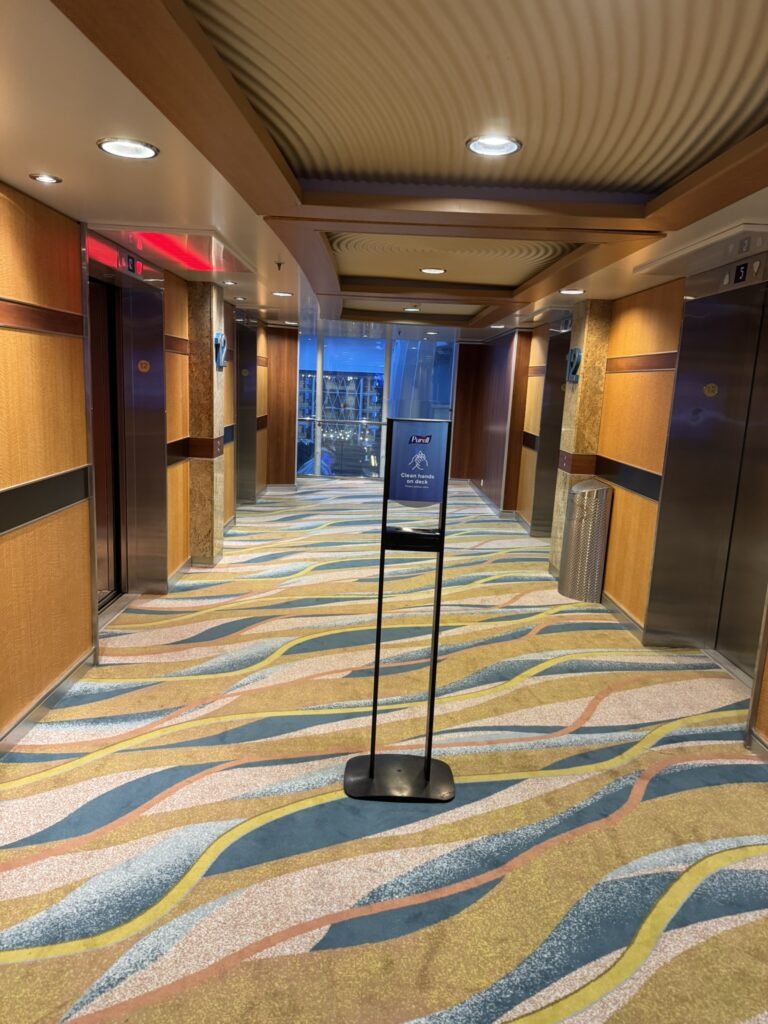 Two sets of elevator doors on Oasis of the Seas, with two elevators on each side in a bright, modern lobby.