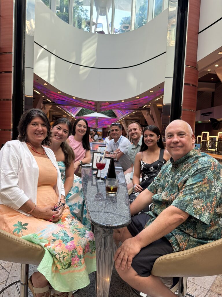 Group seated around a high‑top table on the Rising Tide Bar aboard Oasis of the Seas, enjoying drinks as the bar sits in its lounge setting between decks.