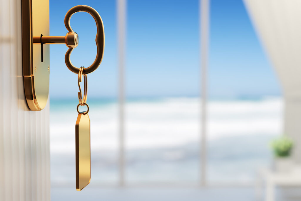 A key turning in a door with the ocean in the background, symbolizing the Royal Caribbean Key Program.