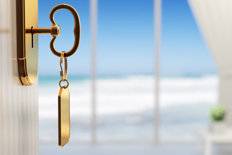 A key turning in a door with the ocean in the background, symbolizing the Royal Caribbean Key Program.