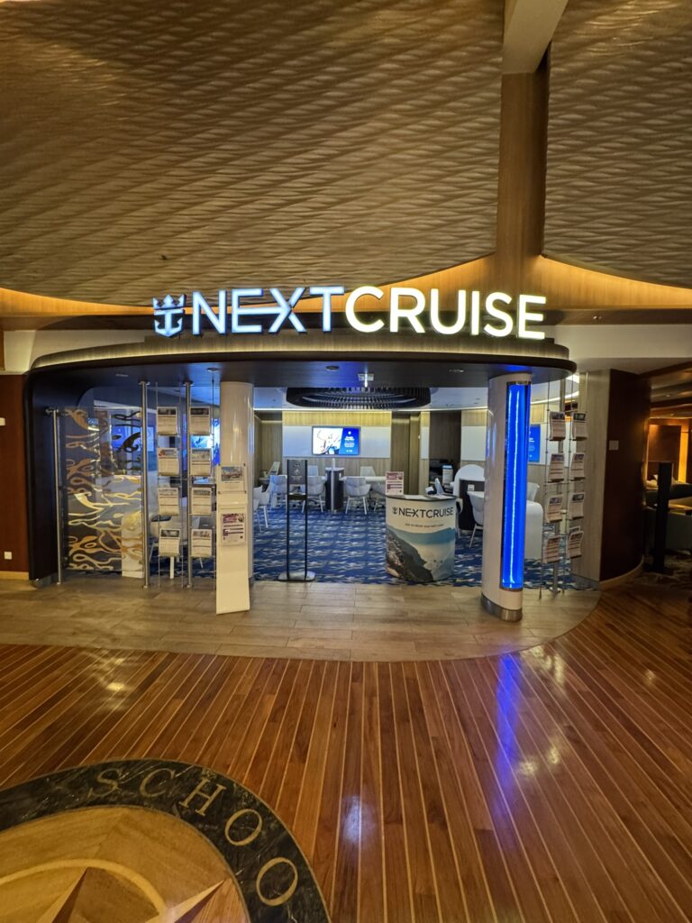 Entrance to the onboard NextCruise office on a Royal Caribbean ship, illustrating the experience of using Royal Caribbean’s Next Cruise Program to book a future sailing.