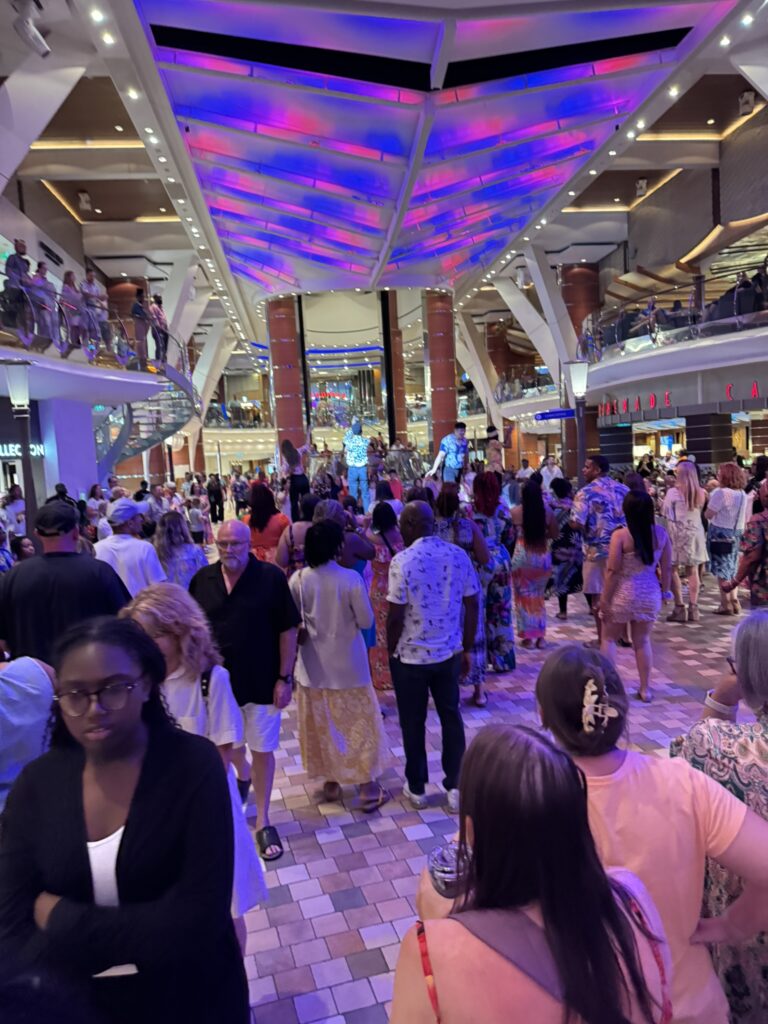 Busy Royal Promenade on Oasis of the Seas with crowds walking through the main walkway.