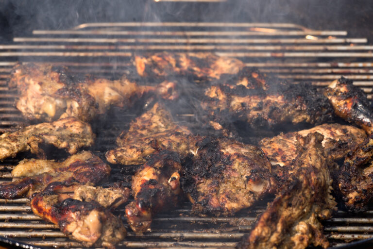 Jerk chicken grilling over open flames on a traditional pimento‑wood barbecue at Scotchies in Jamaica.