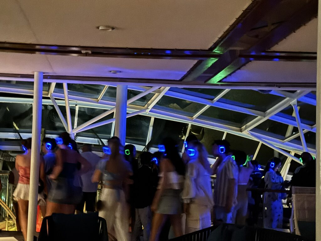 Guests dancing at the Silent Disco party on Royal Caribbean’s Oasis of the Seas, each wearing glowing LED headphones tuned to different music channels.