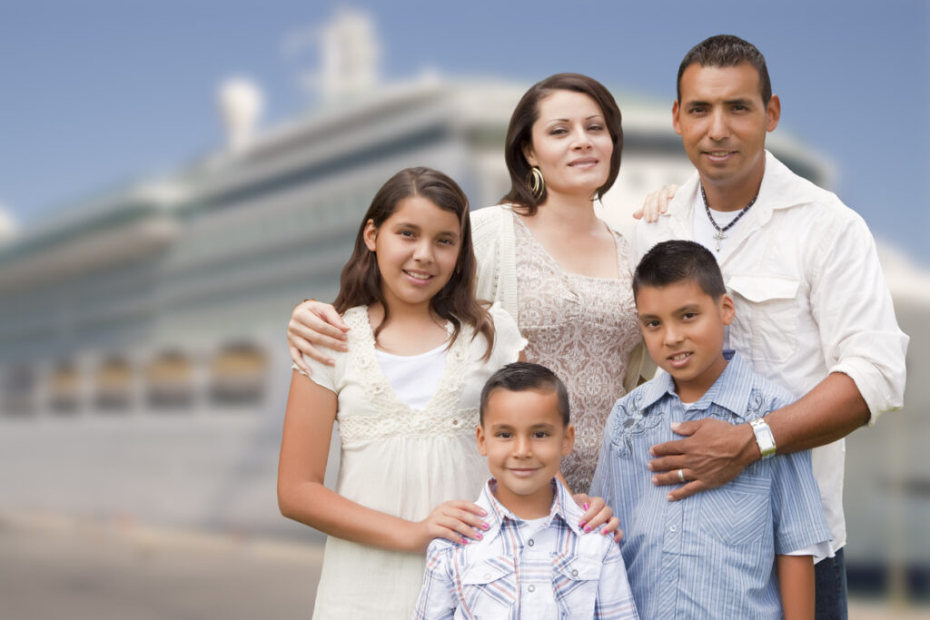 Family of five smiling in front of a cruise ship while planning their cruise budget and travel style.