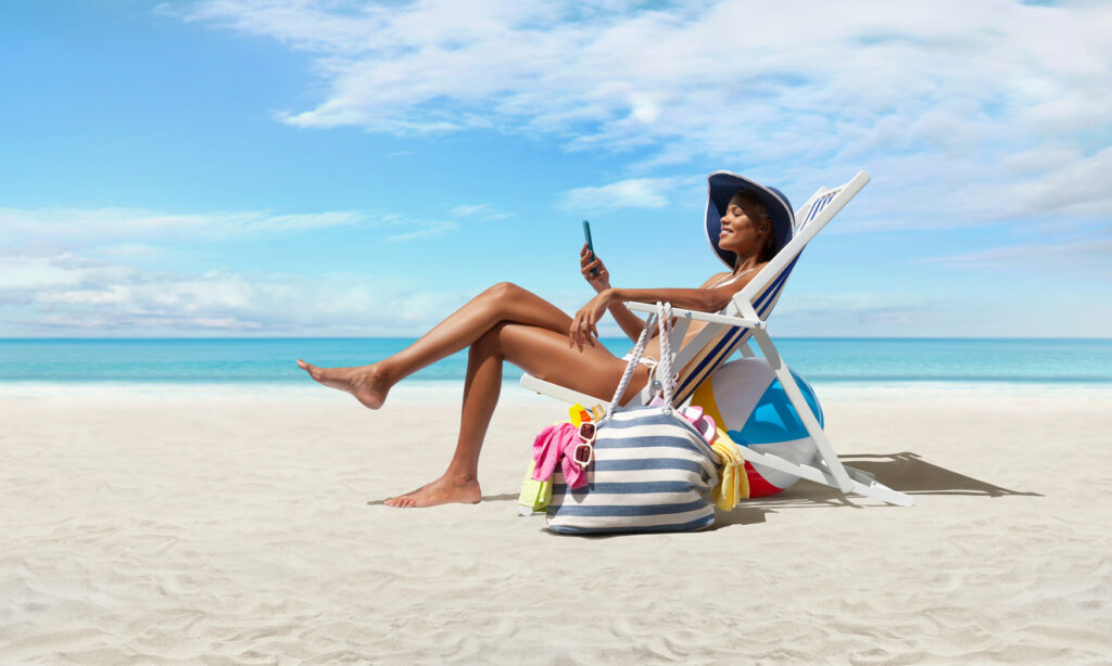 Woman relaxing on a beach chair with a packed beach bag and ocean view, illustrating items for a cruise excursion packing list.