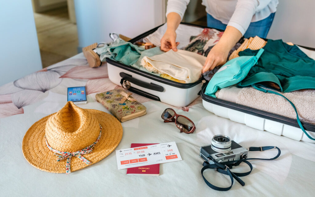 Traveler packing a suitcase on a bed with clothing, accessories, and travel essentials scattered around, illustrating common cruise packing mistakes to avoid.