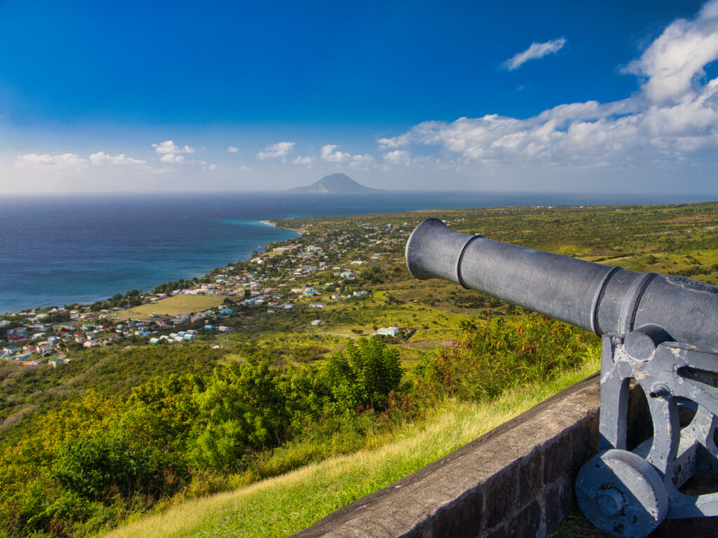 Historic cannon on the battlements of Brimstone Hill Fortress in St. Kitts, overlooking the coastline on a sunny day.