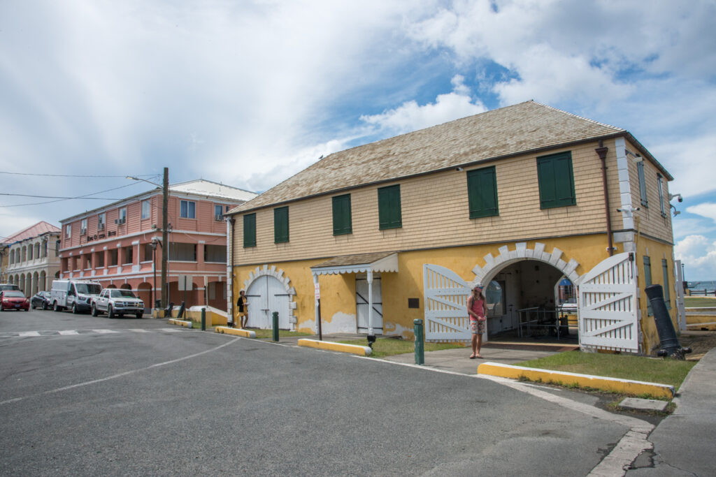 The historic Scale House at Christiansted National Historic Site with a visitor walking nearby.