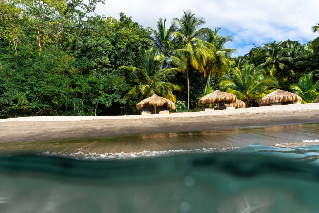 Volcanic sand and clear turquoise water at Anse Chastanet Beach with lush green hillsides in St. Lucia.