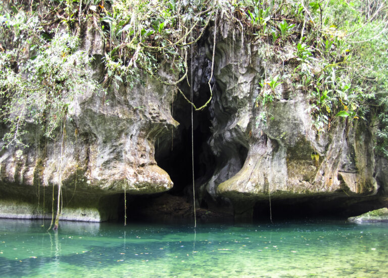 A natural cave opening in the Belize jungle, similar to the limestone formations you’ll see while cave tubing at Nohoch Che’en.