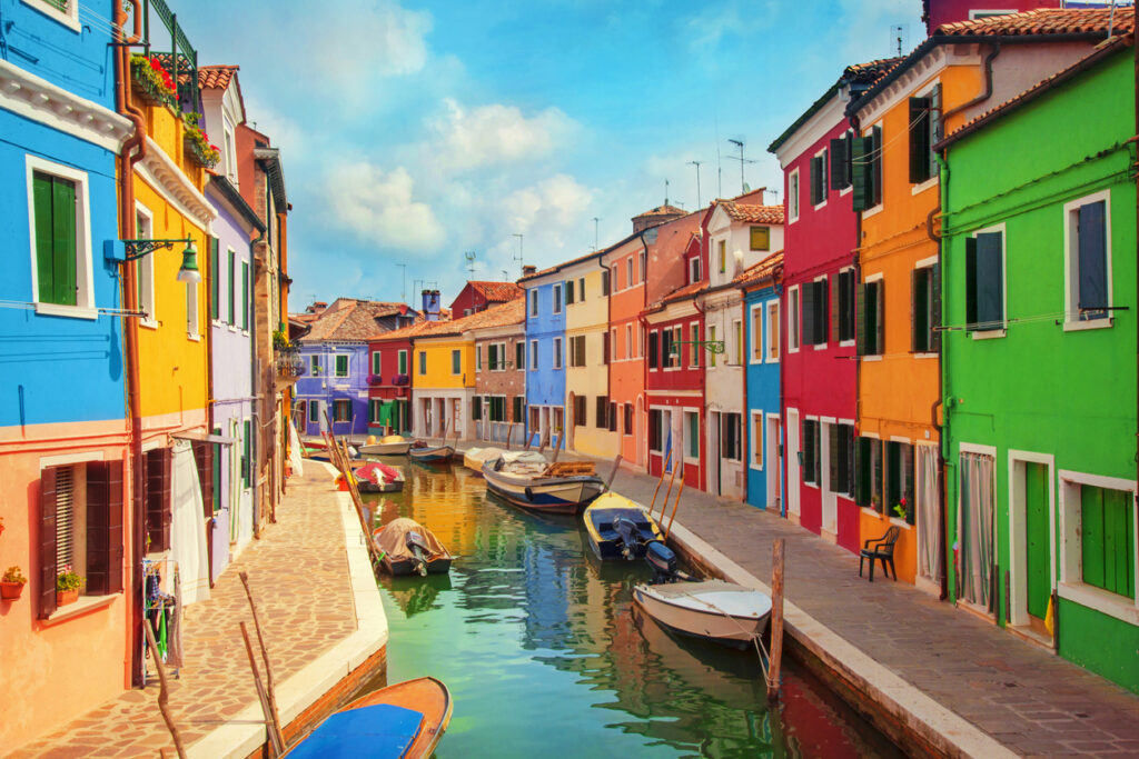 Charming canal and footbridge surrounded by colorful houses on Burano Island.