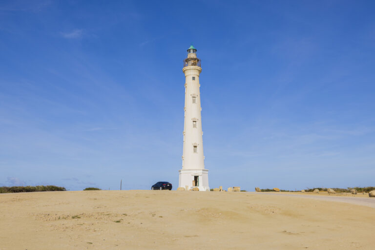 California Lighthouse overlooking Aruba’s rugged northern coastline under a bright blue sky.