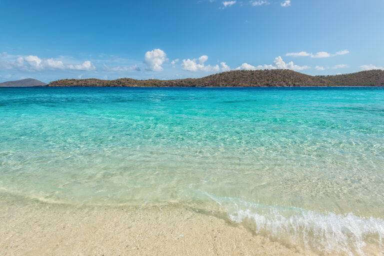 Coki Point Beach in St. Thomas with clear turquoise water and Thatch Cay island in the background.