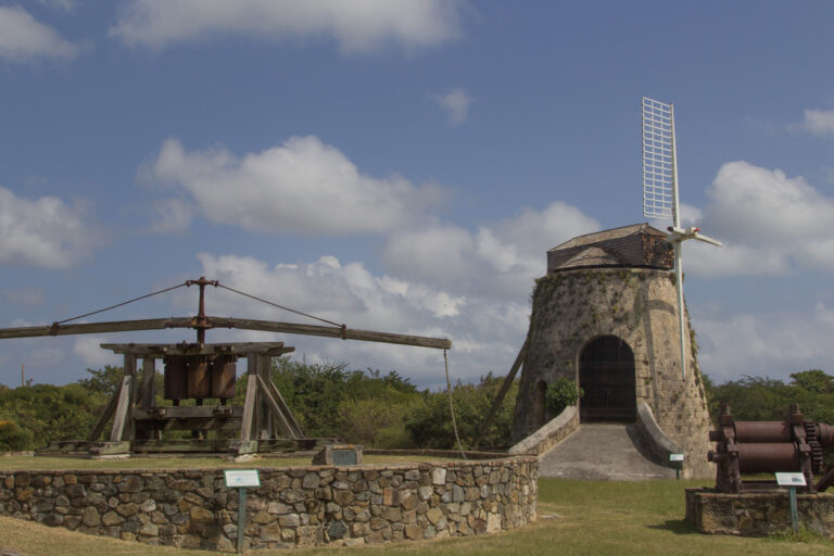 Animal mill and stone windmill on display at Estate Whim Museum in St. Croix, showing historic sugar plantation structures.
