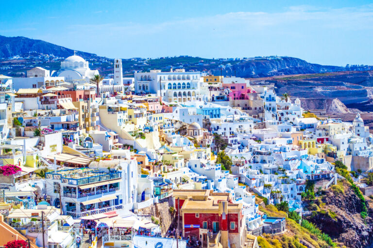 Scenic view of whitewashed buildings of Fira-the capital of Santorini island in the Aegean Sea.Fira’s clifftop location affords views of Nea Kameni island with active volcano