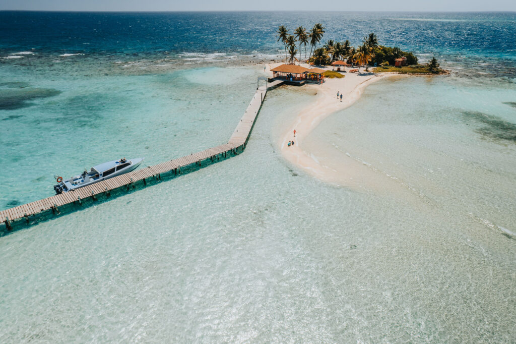Aerial view of Goff’s Caye, a small white‑sand island surrounded by turquoise water in Belize
