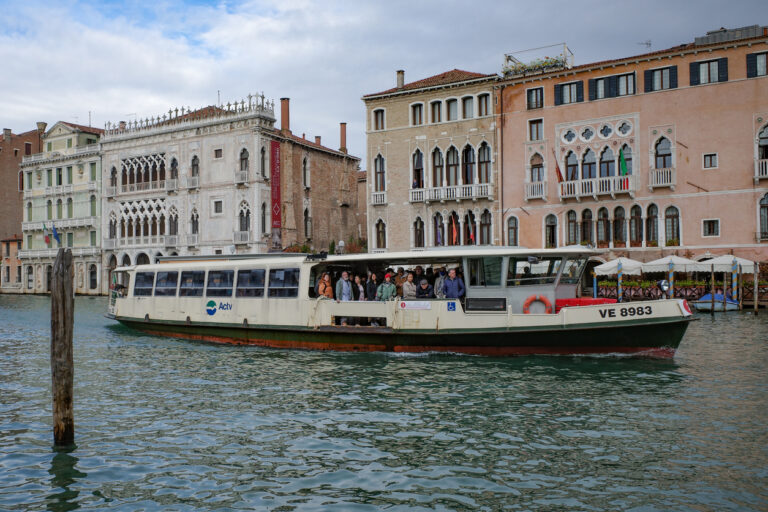 Vaporetto cruising along the Grand Canal in Venice with buildings in the background.