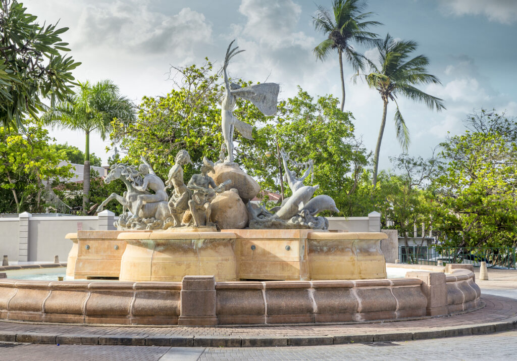 Paseo de la Princesa fountain in Old San Juan, Puerto Rico, surrounded by historic walkways and lush greenery along the waterfront promenade.