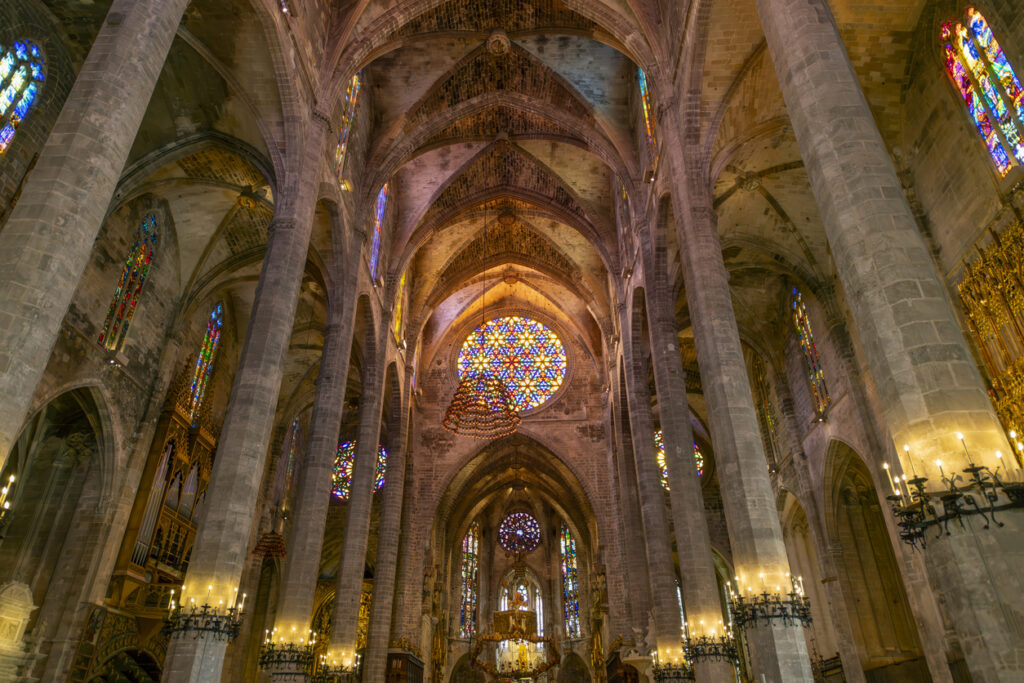 The ornate gothic interior with stained glass windows and imposing columns in the Palma de Santa Maria Cathedral of Palma, or La Seu, in the Mediterranean city of Palma de Mallorca Spain.