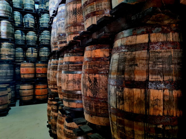 A long corridor of stacked rum barrels aging quietly inside the Mount Gay distillery.