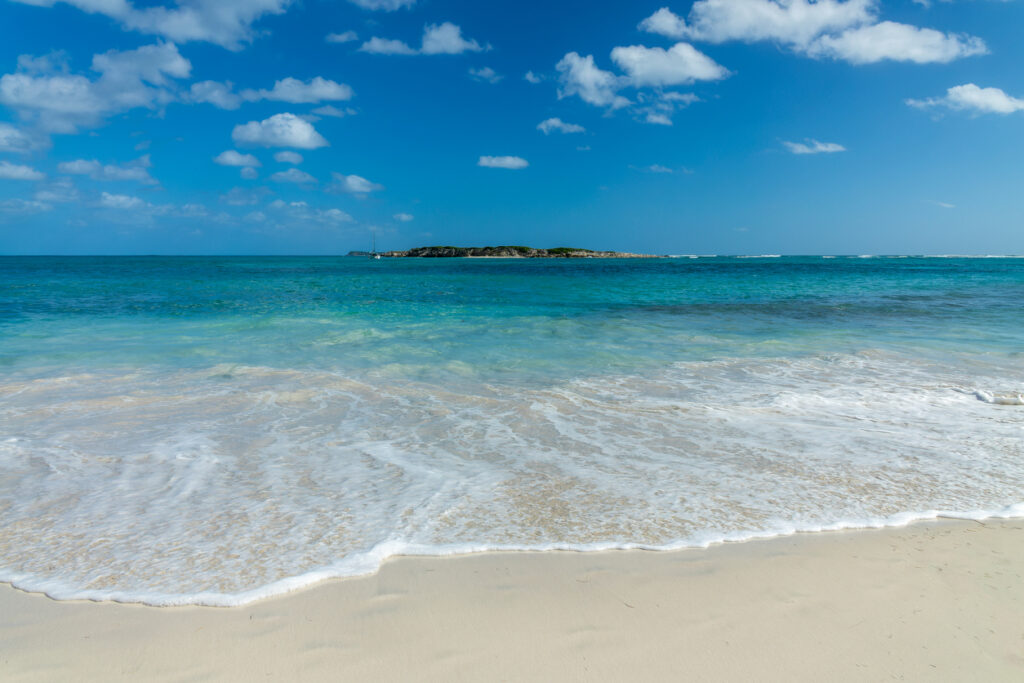 Scenic view of Orient Bay Beach in St. Martin with turquoise water and Caye Verte island offshore.
