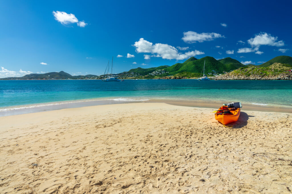 Scenic view of Pinel Island on the French side of St. Martin, with calm turquoise water and a sandy beach.