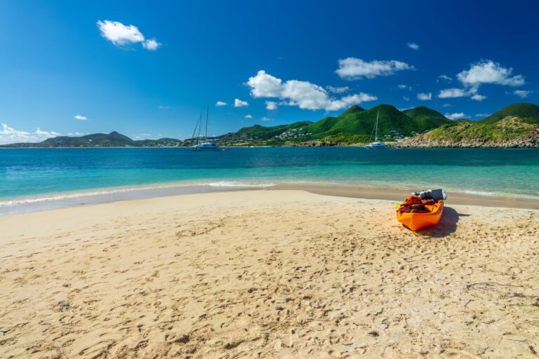 Scenic view of Pinel Island on the French side of St. Martin, with calm turquoise water and a sandy beach.