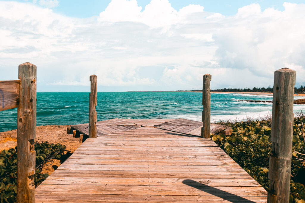 Peaceful wooden bridge along the Piñones coastline in Puerto Rico, overlooking La Posita Beach with ocean views and natural scenery.