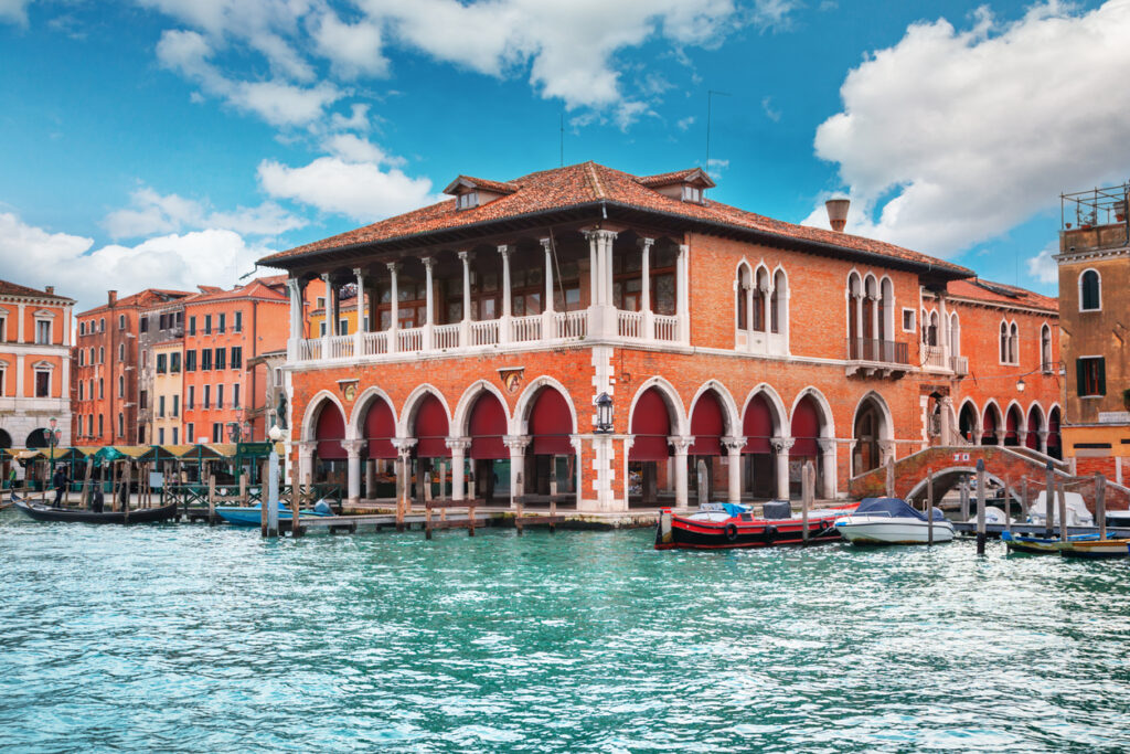 Waterfront view of the Rialto Bridge with gondolas and shops along the canal.