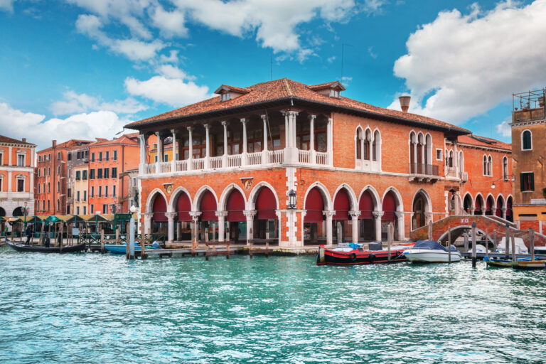 Waterfront view of the Rialto Bridge with gondolas and shops along the canal.