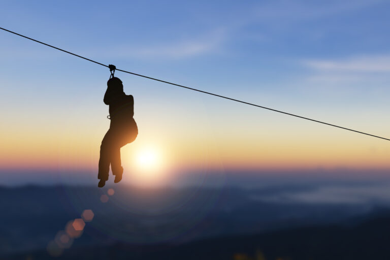 Silhouette of a woman ziplining against a warm sunset sky, capturing the adventurous canopy‑tour experience in Roatán.