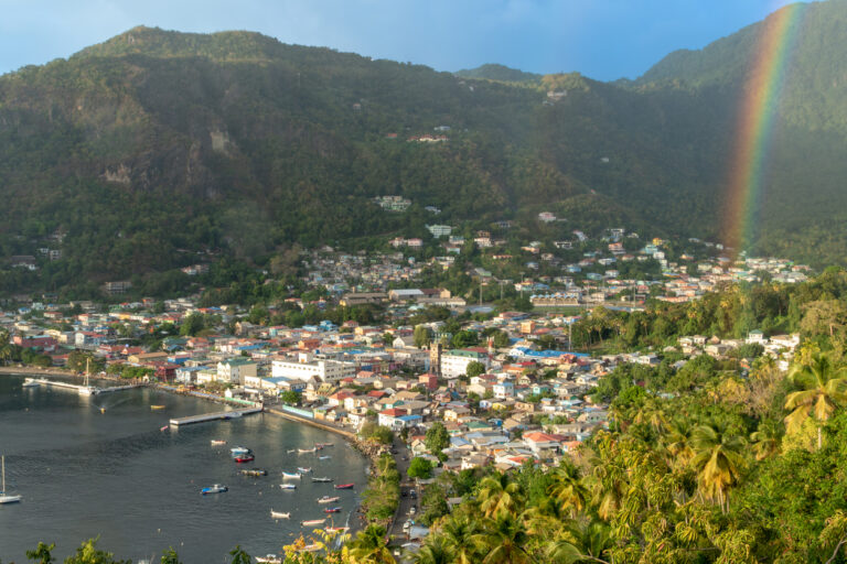 Scenic view of the village of Soufrière on St. Lucia’s west coast with a rainbow arching over the colorful hillside and bay.