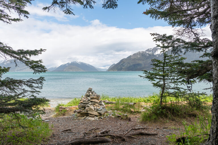 Stone cairn marking the entrance to the beach along the Battery Point Trail in Haines, Alaska, with views overlooking the Chilkat Inlet.