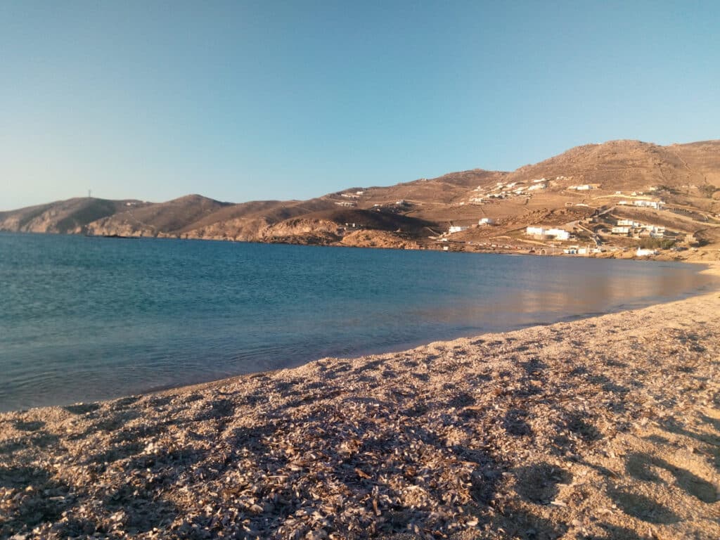 A view of the sandy Ftelia beach, at sunset. In the distance one can see the few buildings of the area.