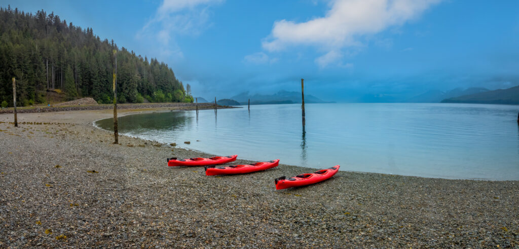 Kayak on the calm, protected waters near Icy Strait Point in Hoonah, Alaska, with forested mountains and coastal scenery in the distance.