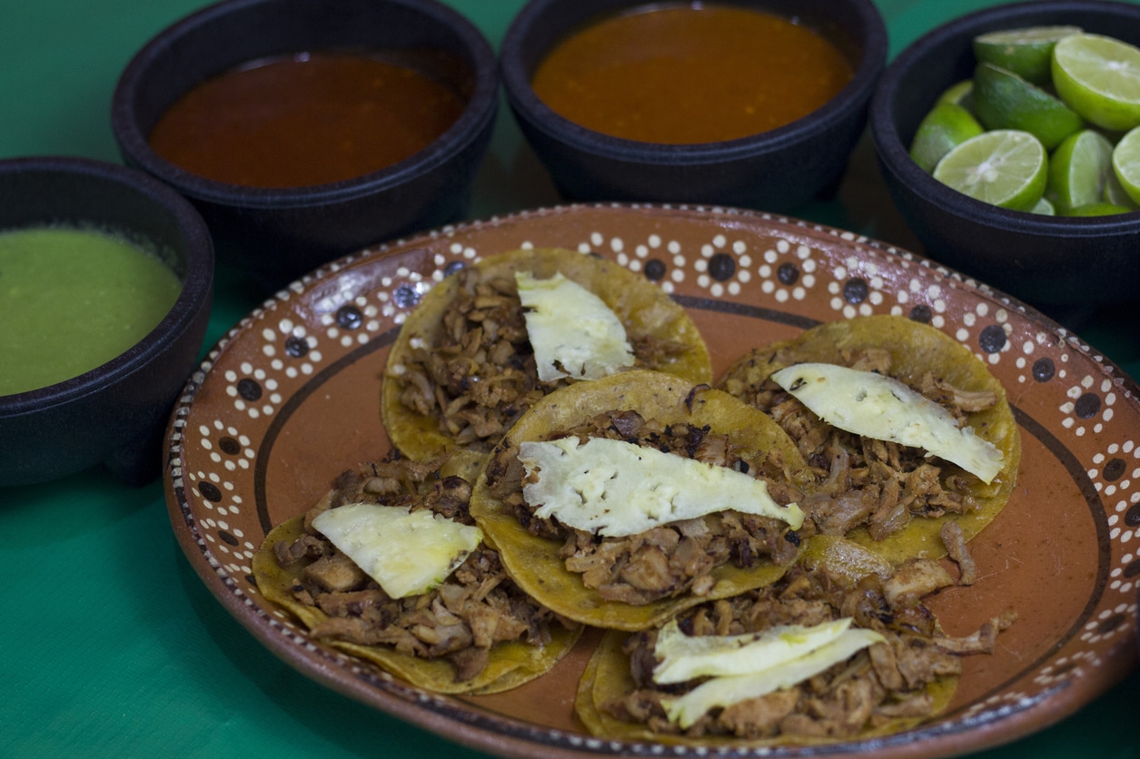 Plate of authentic Mexican tacos served with fresh salsas and lime wedges in Cozumel.