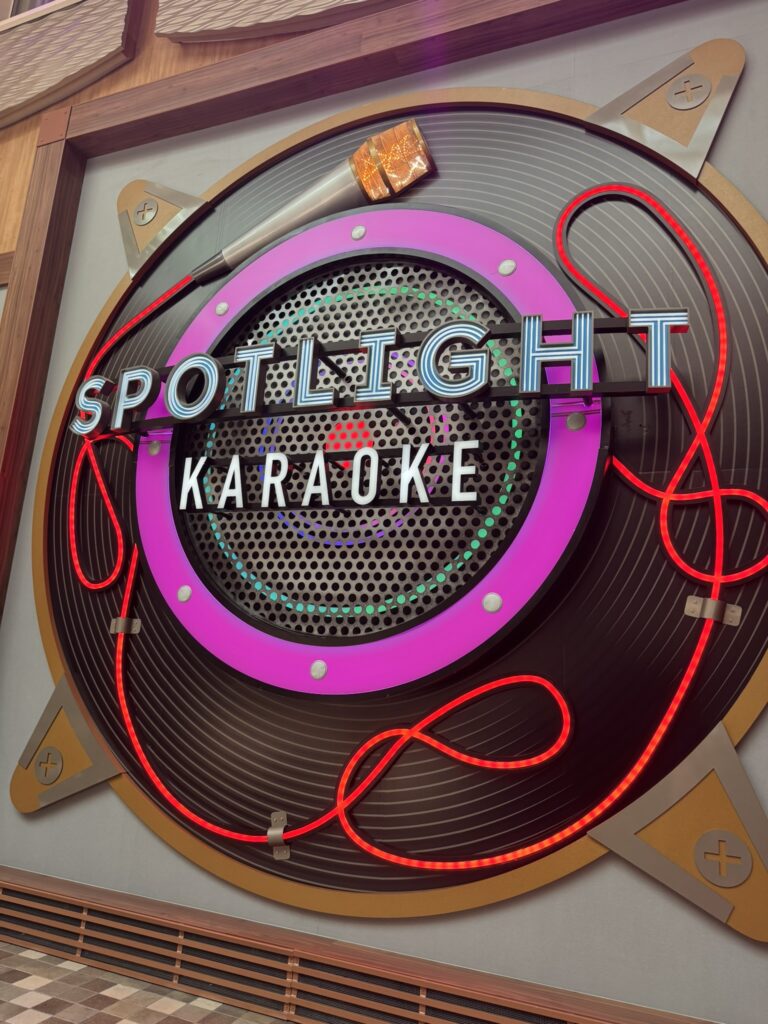 Neon Spotlight Karaoke sign with bold lettering, glowing rings, and a microphone above the entrance.