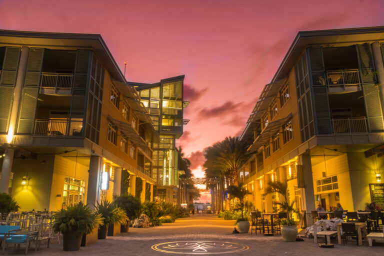 Illuminated pedestrian walkway at The Paseo in Camana Bay during sunset, showcasing the modern waterfront atmosphere of Grand Cayman