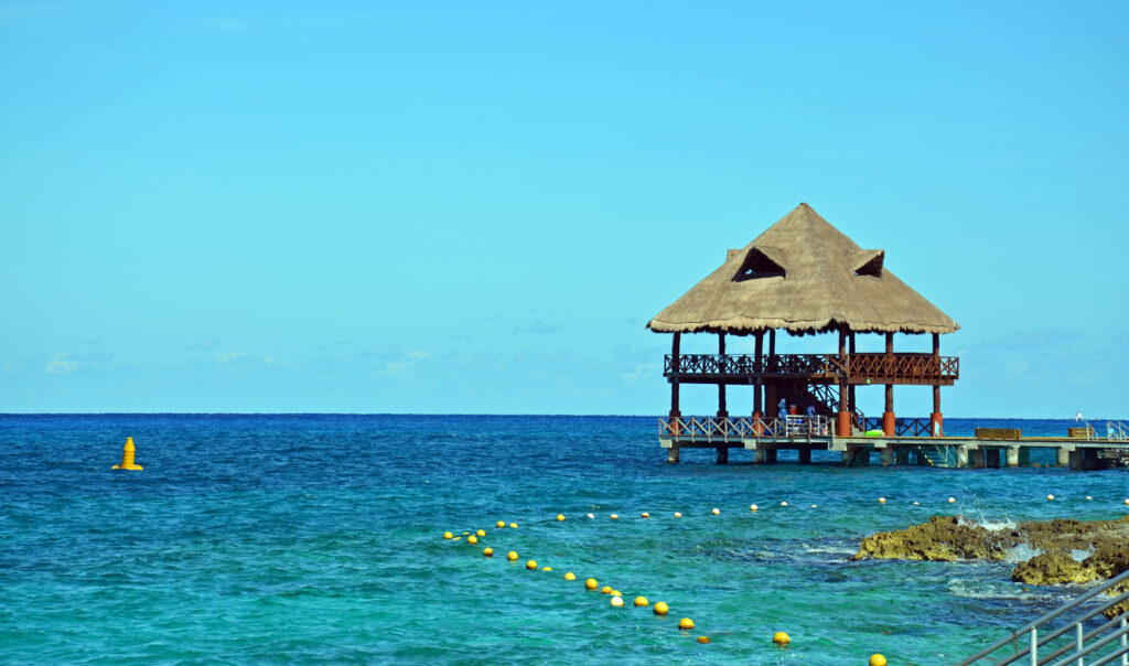 Peaceful early‑morning beach scene at Chankanaab Beach Adventure Park with calm water and a kid‑friendly shoreline.