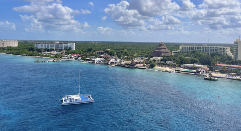 Catamaran sailing along Cozumel’s coastline with guests relaxing on deck.
